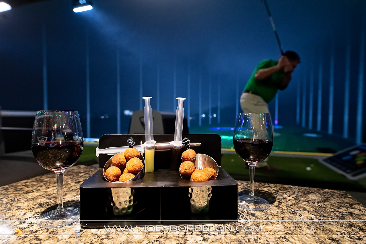 Top Golf signature donut holes and wine in forefront; man golfing in background